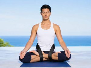Meditation Knee Straps helping a man maintain a stable cross-legged meditation posture outdoors, featuring black knee support straps designed to improve hip alignment, reduce knee strain, and provide greater comfort during extended meditation sessions.